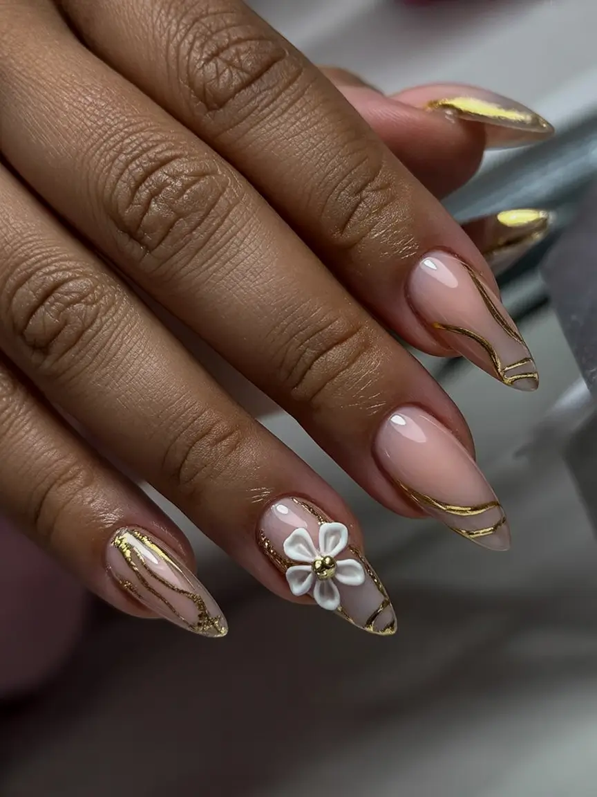 must try spring nails for dark skin 2026 Nude Almond Nails with Gold Lines and Floral Detail