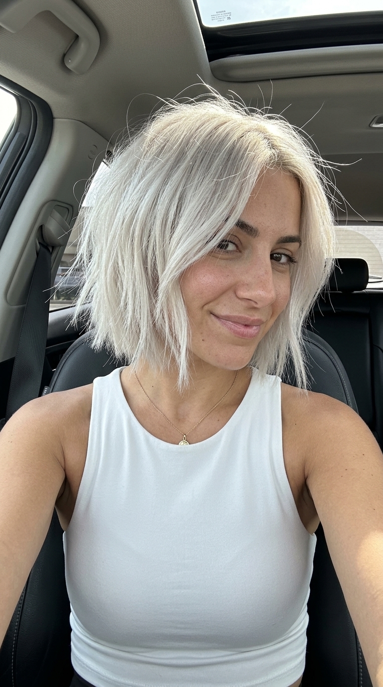 chin-length icy platinum bob haircut with textured layers and root shadow for high-fashion event