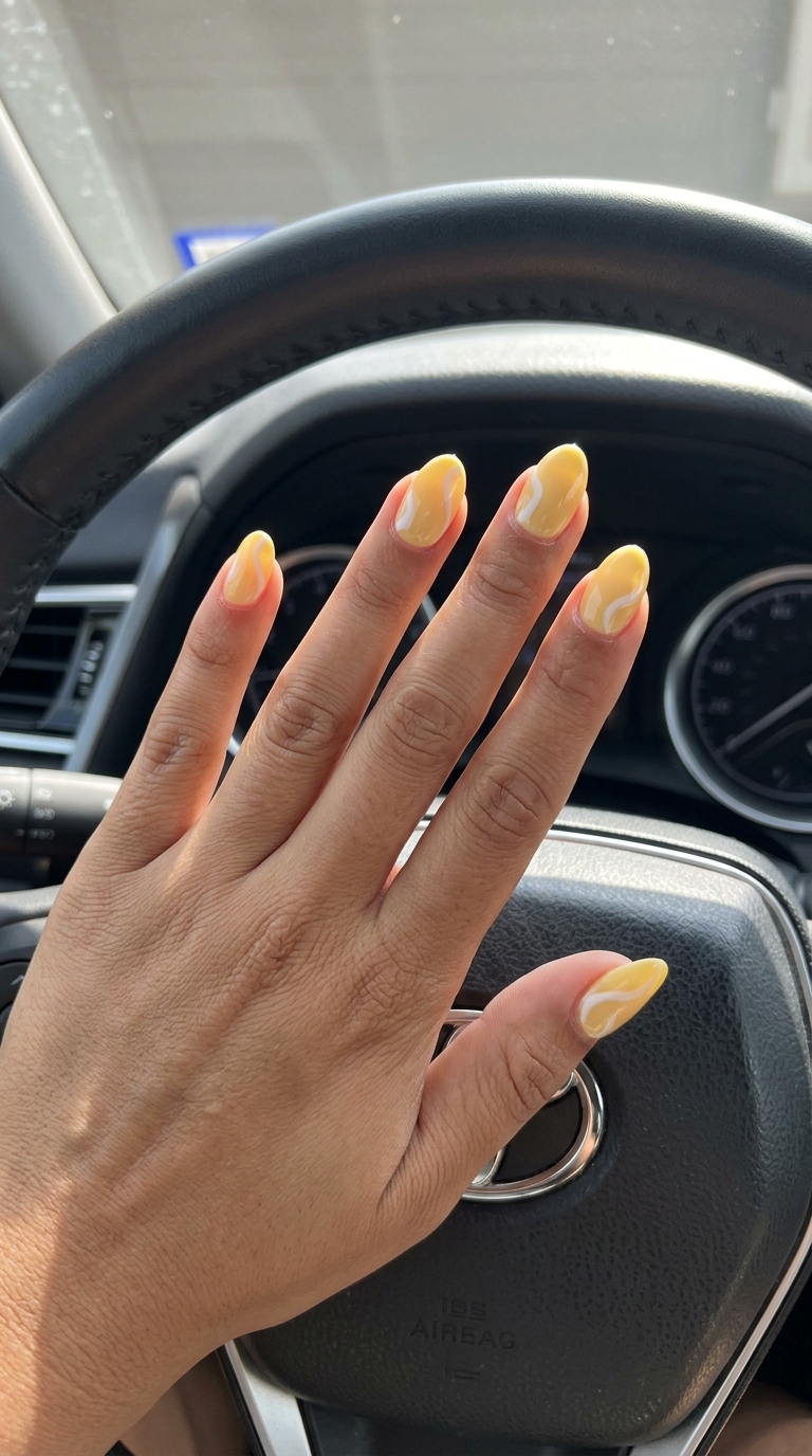 Oval Summer Nails 2026: Butter Yellow Swirls Butter yellow oval nails with abstract white swirls for summer 2026. Chic and artistic for casual outings.
