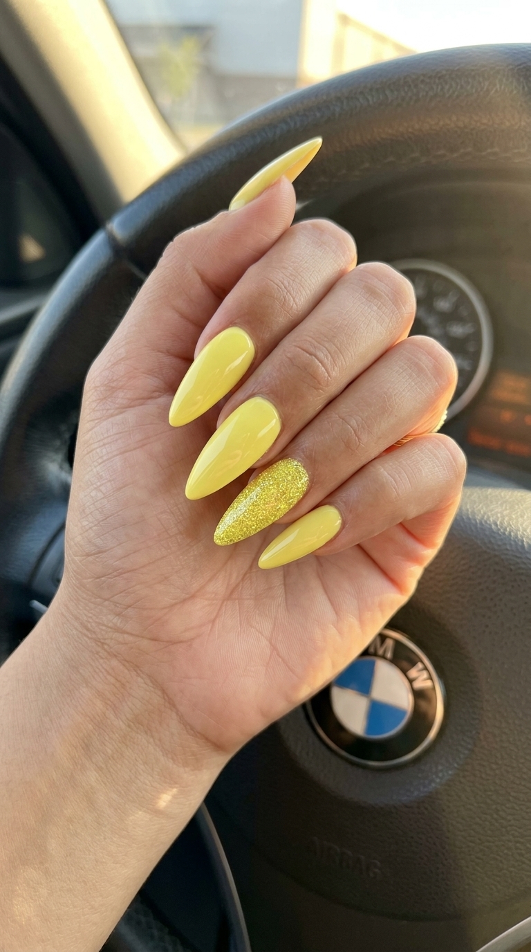 Glamorous yellow summer nails 2026: Lemon yellow with a sparkling fine glitter accent on medium almond nails.