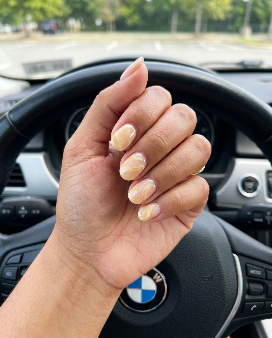 Romantic yellow summer nails 2026: Milky butter yellow marble veining on a sheer nude base for casual events.