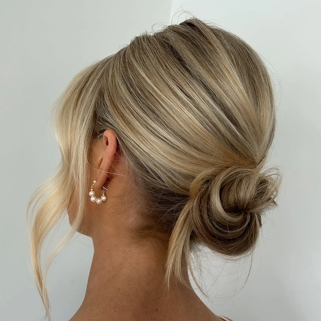 bridesmaid hairstyling Minimalist Low Bridesmaid Bun With Soft Blonde Face Framing