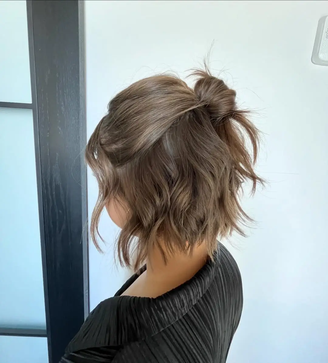 Fall hairstyles for short hair 2026 A Playful Mini Top Knot for Textured Short Hair