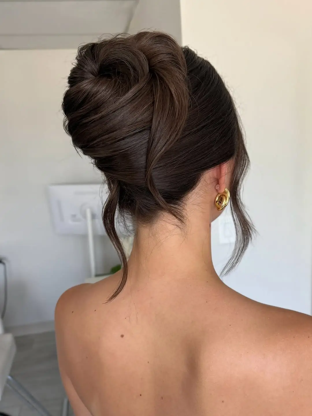 Fall hairstyles for wedding guests 2026 Polished Sculptural Bun with Face-Framing Strands