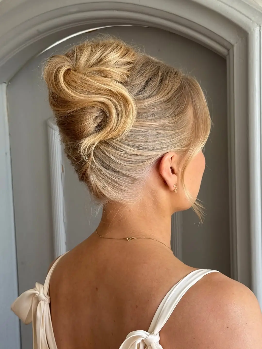 Fall hairstyles for wedding guests 2026 Elegant Sculpted High Bun with Vintage Volume