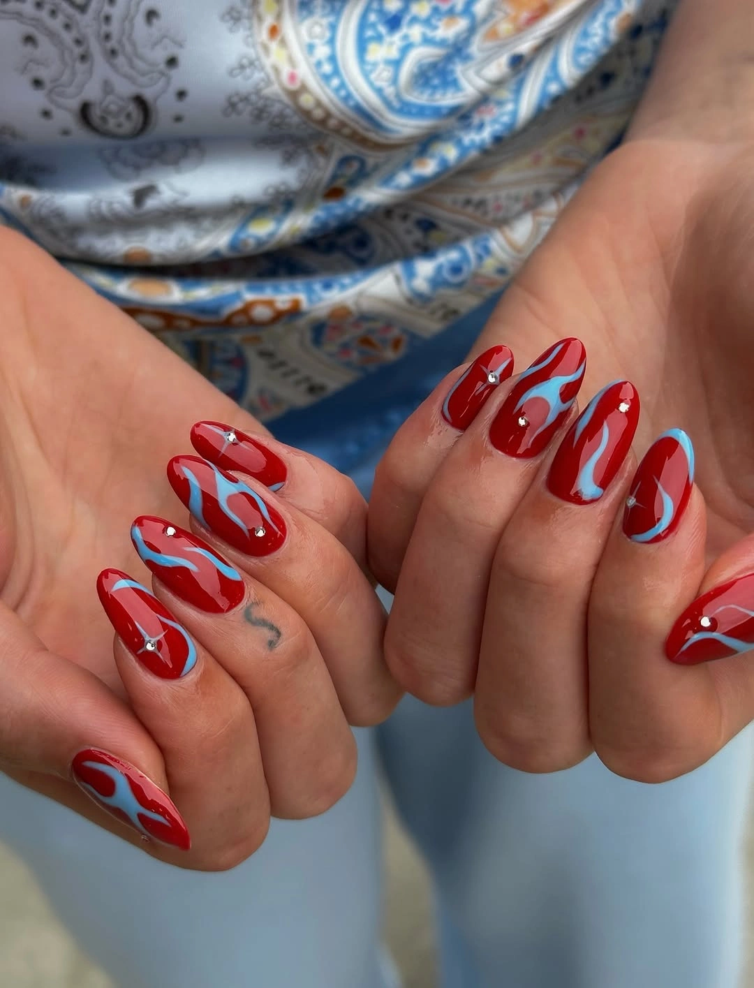 Fall red nails 2026 Bright Red Nails With Modern Blue Swirls