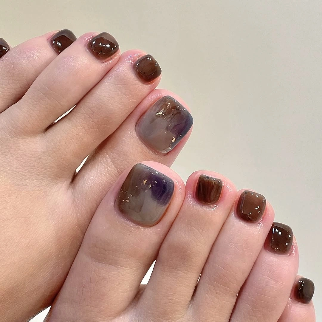 fall toe nails colors 2026 Smoky Brown Jelly Pedicure with Delicate Gold Flakes