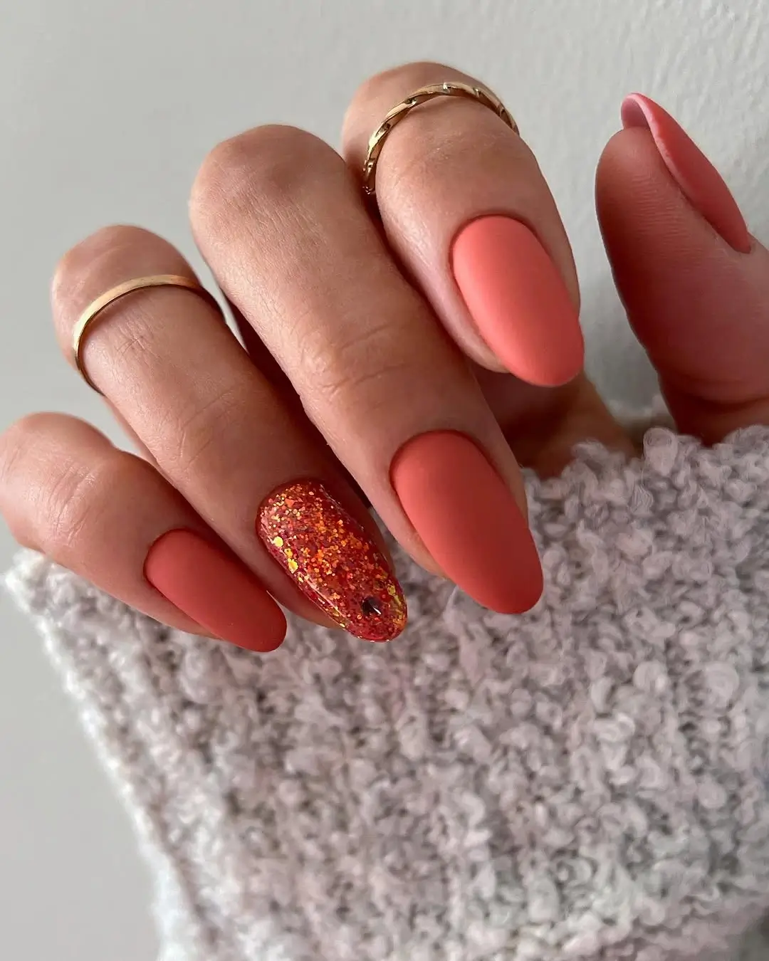 fall trendy nails 2026 matte coral almond nails with red glitter accent