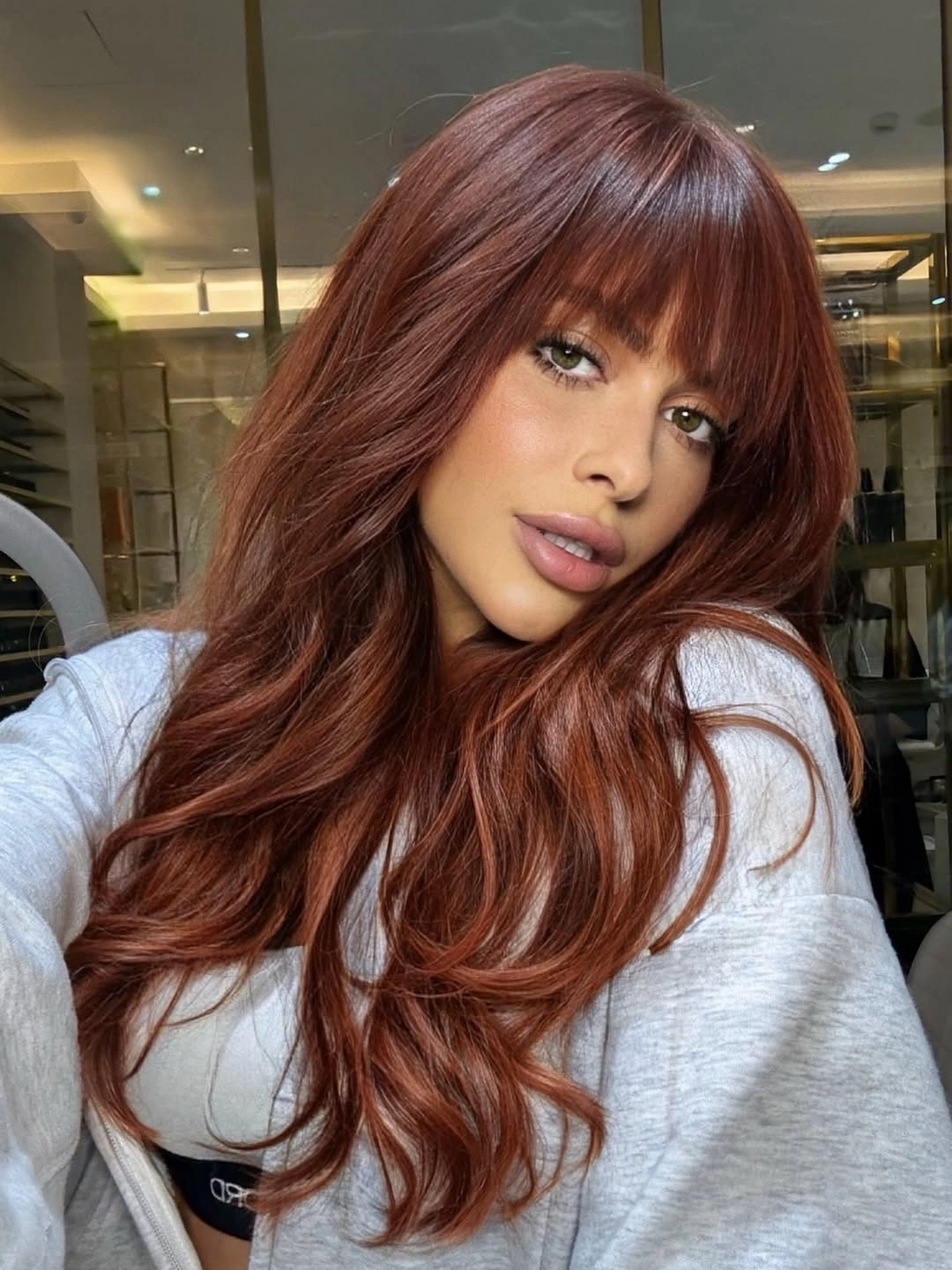 September hair colour trends 2026 warm auburn red with full feathered bangs