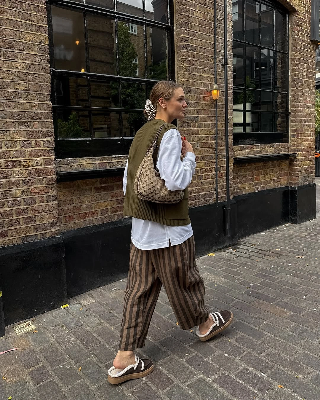 September outfit ideas 2026 Olive sweater vest and striped trousers for London-inspired casual style