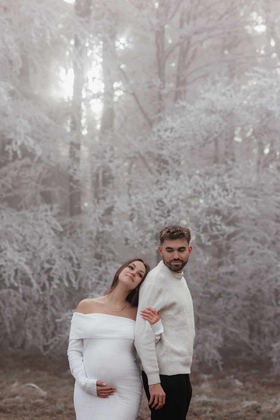 White Off-the-Shoulder Dress in a Snowy Forest Setting White Off-the-Shoulder Dress in a Snowy Forest Setting — Winter Maternity Outfits